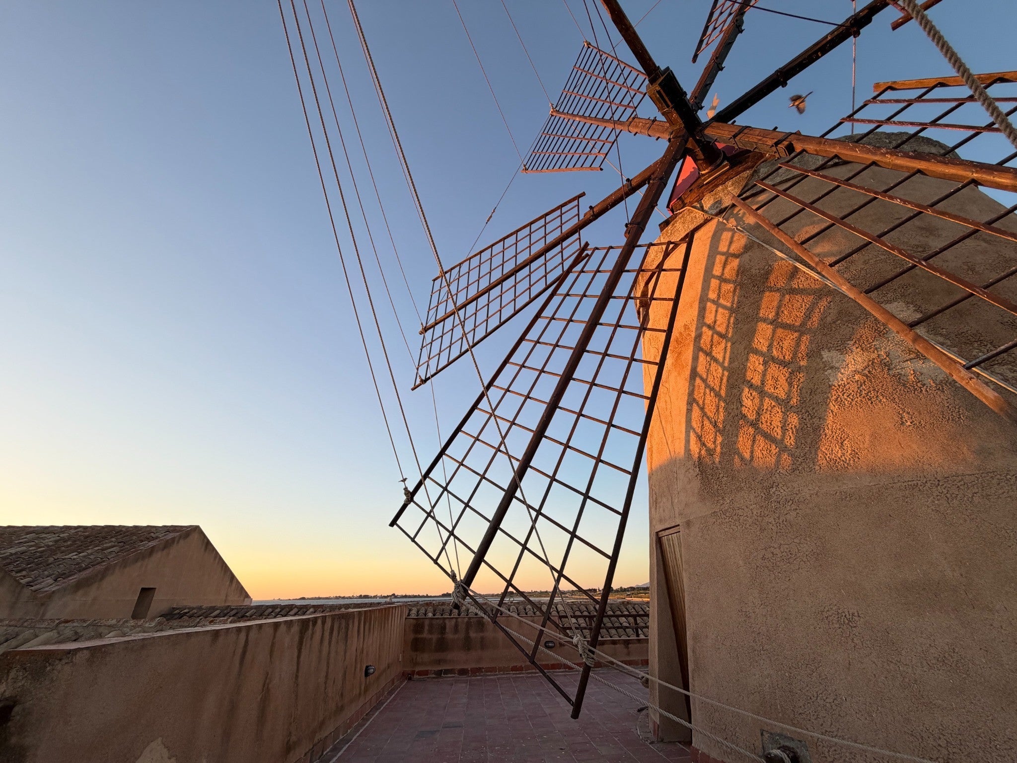 Warm evening light on a windmill and its wooden sails during our travels in Italy