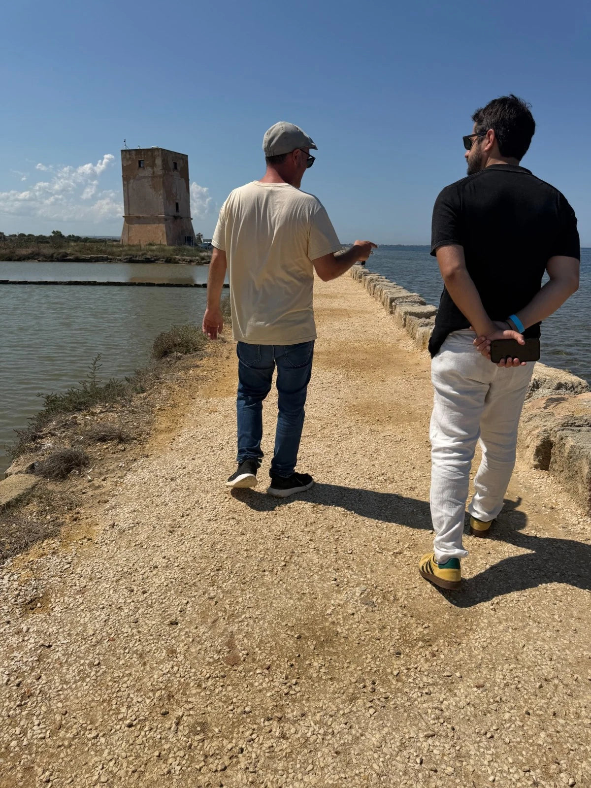 Two people walking beside a salt pan