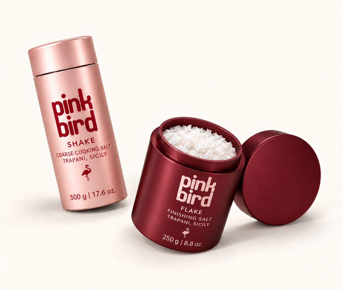 Product visualization of blush Shake and burgundy Flake bottles, with an open Flake bottle and lid. Packaging and salt texture are illustrative.